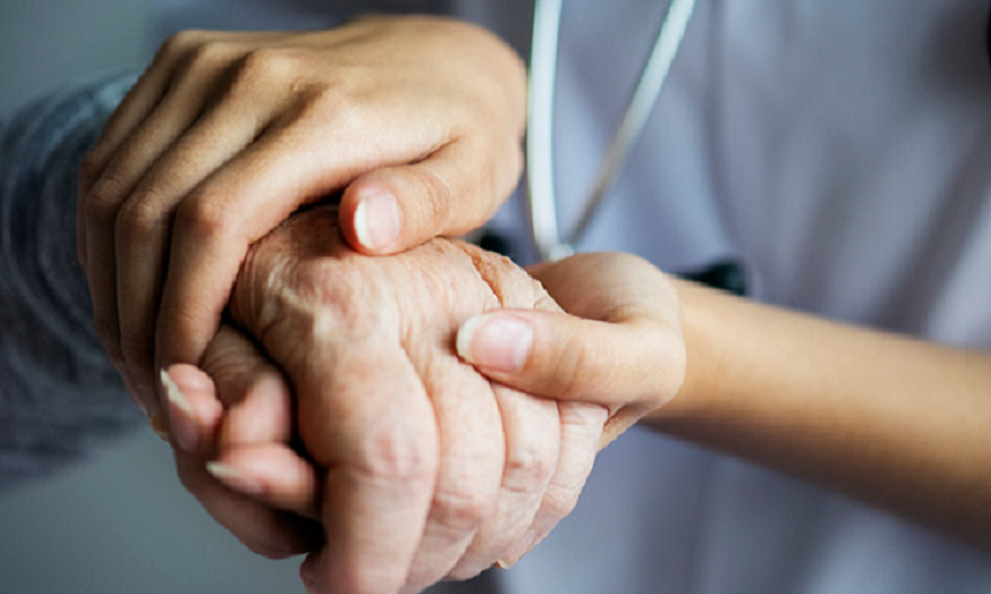 ręce młodej pielęgniarki trzymające dłoń osoby starszej