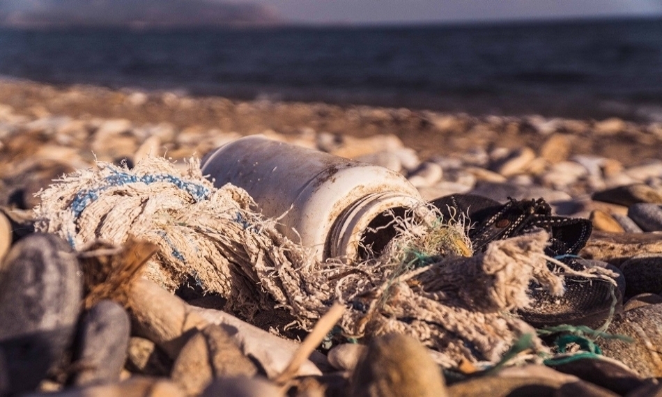 Zdjęie przedstawia zbliżenie śmieci leżących na plaży.